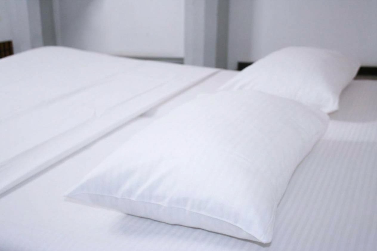 A bedroom with a white bed and a wooden headboard