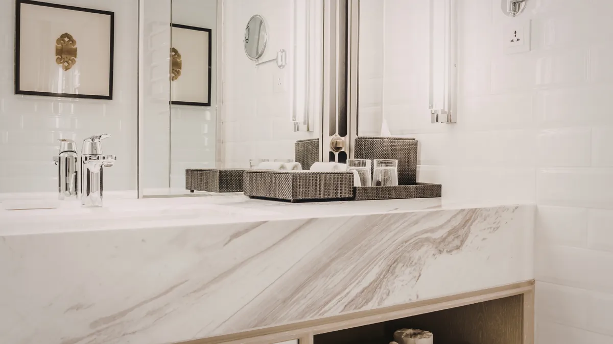A marble-topped vanity with a vessel sink and gold-tone fixtures in a Manhattan bathroom