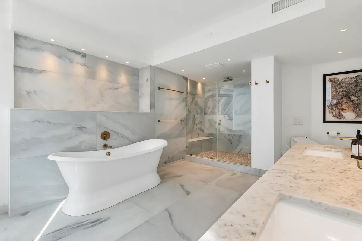 A marble bathroom in Manhattan with a freestanding soaking tub and glass shower