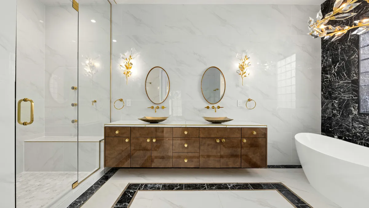 A Long Island bathroom with a wood double vanity, oval mirrors and a freestanding tub