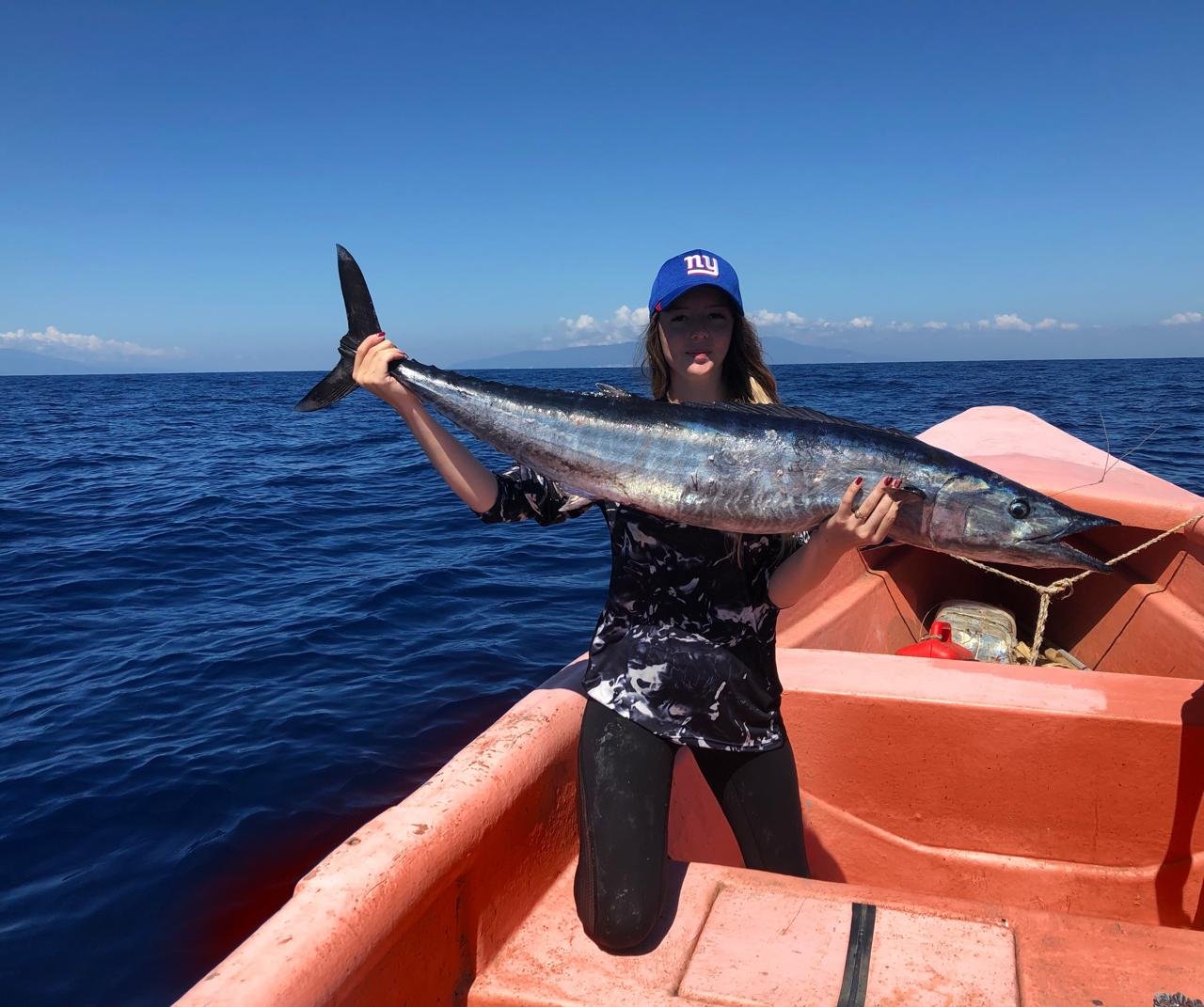 Une personne à bord d’une embarcation, tenant un poisson en haute mer