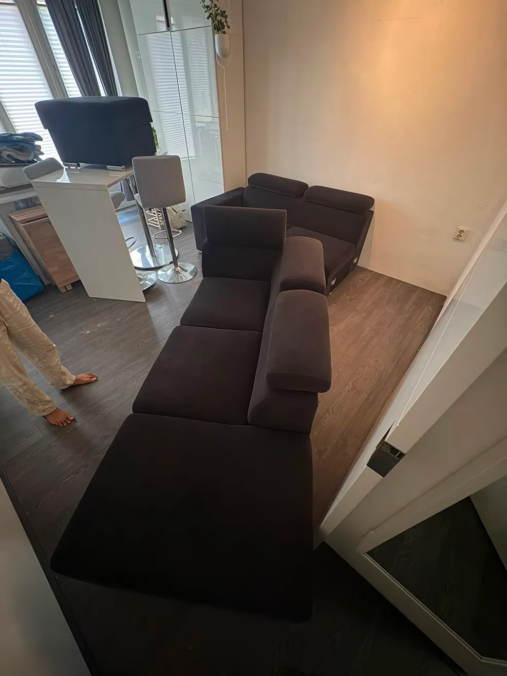 Woonkamer met een donkere bank in losse delen en andere meubels