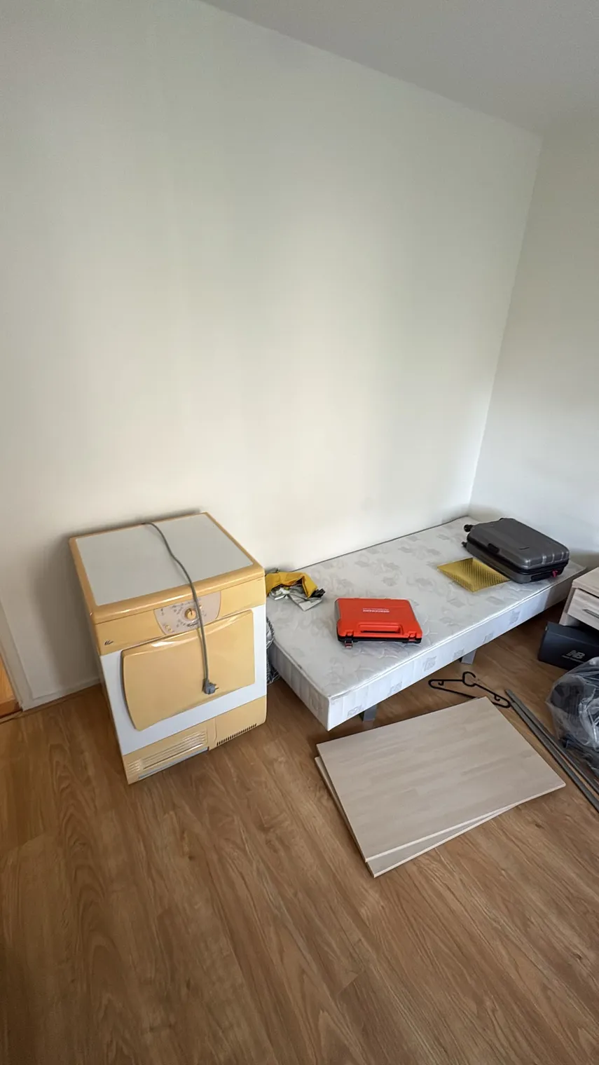 Kamer met losse meubelpanelen, een bedbodem en een apparaat tijdens het leeghalen