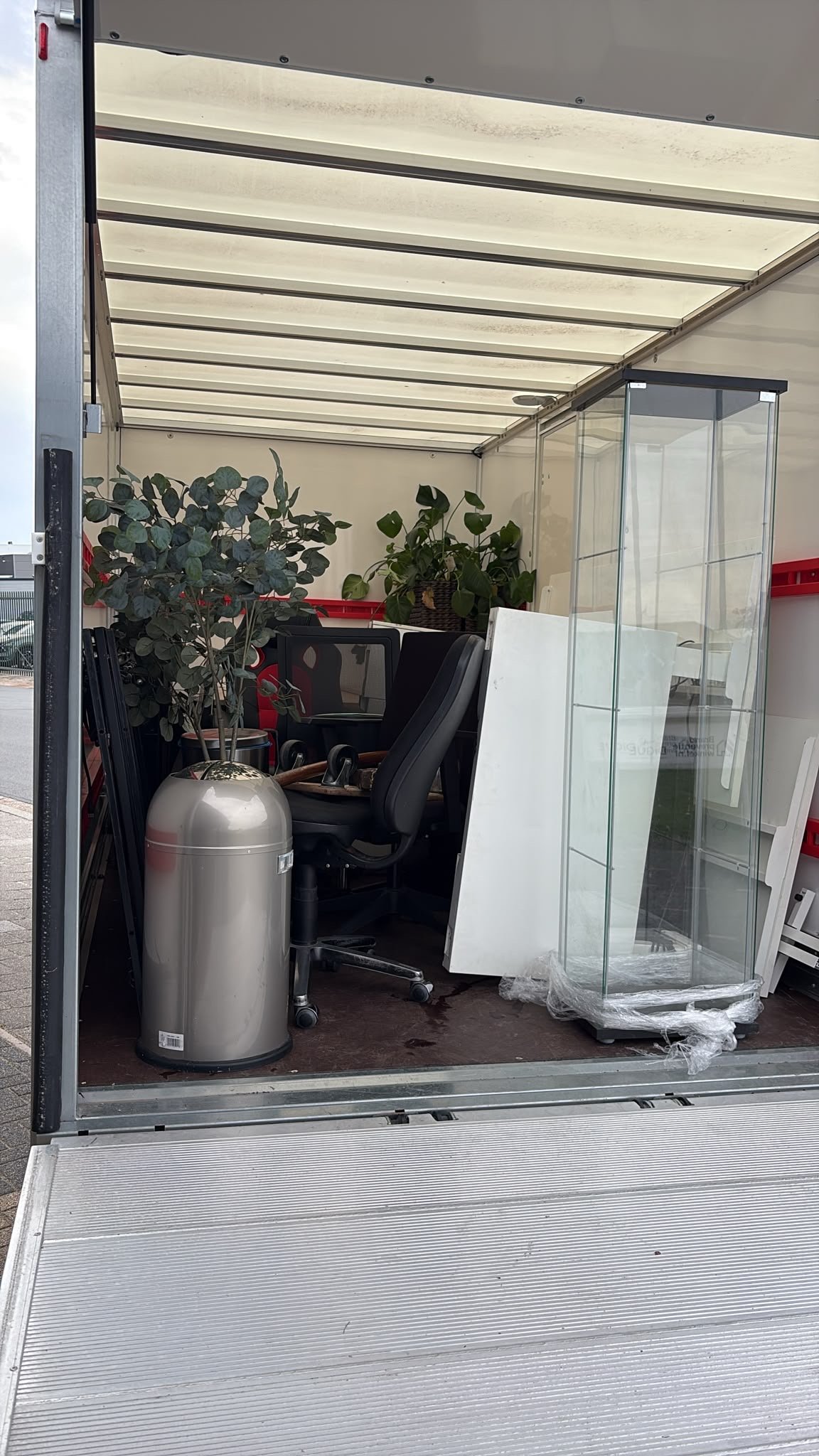 Bureaustoelen, planten en een vitrinekast in de wagen.
